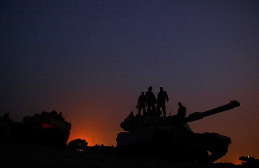 Tripulación sobre un carro de combate al atardecer